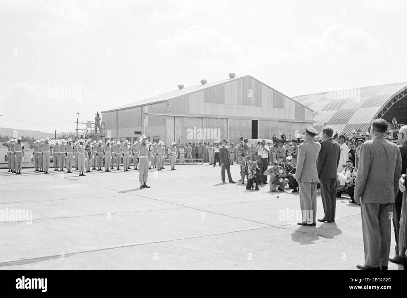 Inspection tour of NASA installations: Huntsville Alabama, Redstone Army Airfield and George C. Marshall Space Flight Center, 9:35AM. President John F. Kennedy (right, back to camera) receives military honors upon arrival at Redstone Army Airfield, Redstone Arsenal, Huntsville, Alabama; Commanding General of the U.S. Army Missile Command, Major General Francis J. McMorrow (saluting), stands left of President Kennedy. Standing at far right in foreground: Administrator of the National Aeronautics and Space Administration (NASA), Dr. James E. Webb; Senator Alexander Wiley of Wisconsin (mostly out Stock Photo