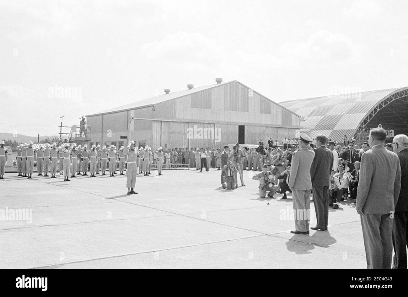 Inspection tour of NASA installations: Huntsville Alabama, Redstone Army Airfield and George C. Marshall Space Flight Center, 9:35AM. President John F. Kennedy (right, back to camera) receives military honors upon arrival at Redstone Army Airfield, Redstone Arsenal, Huntsville, Alabama; Commanding General of the U.S. Army Missile Command, Major General Francis J. McMorrow (saluting), stands left of President Kennedy. Standing at far right in foreground: Administrator of the National Aeronautics and Space Administration (NASA), Dr. James E. Webb; Senator Alexander Wiley of Wisconsin (partially Stock Photo