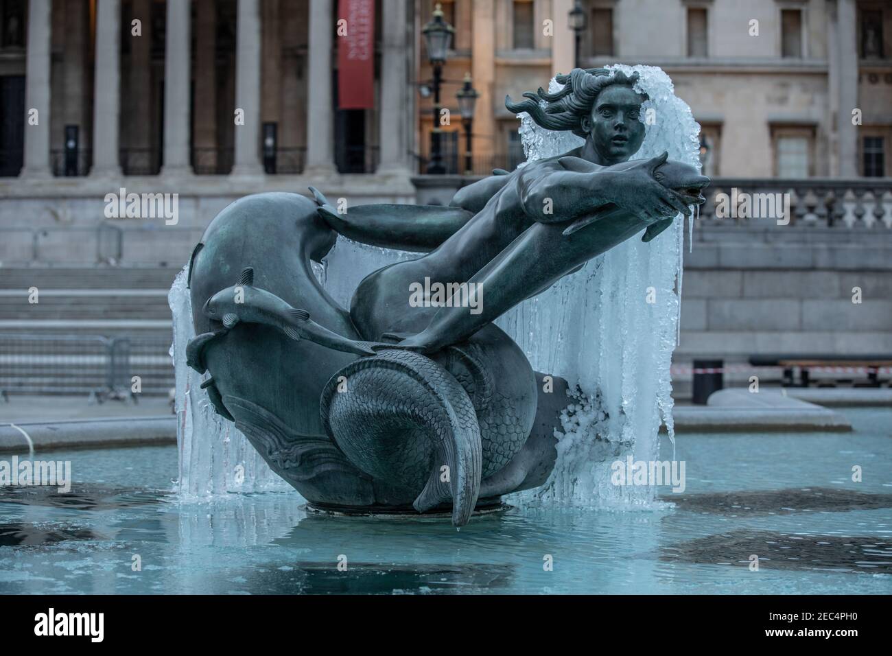 Frozen statue in Trafalgar Square in the foreground of National Gallery after temperatures hit sub-zero temperatures in London during February 2021. Stock Photo