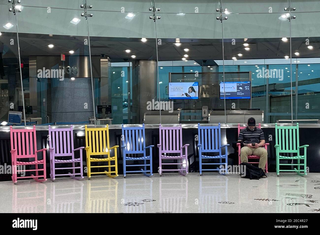 A man sits alone in Terminal D of the Miami International Airport, Saturday, Feb. 13, 2021, in