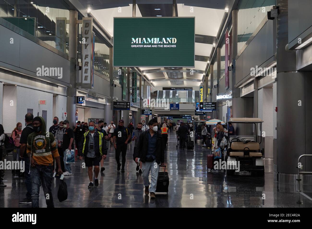 People walk through Terminal D of the Miami International Airport, Saturday, Feb. 13, 2021, in Miami. Stock Photo