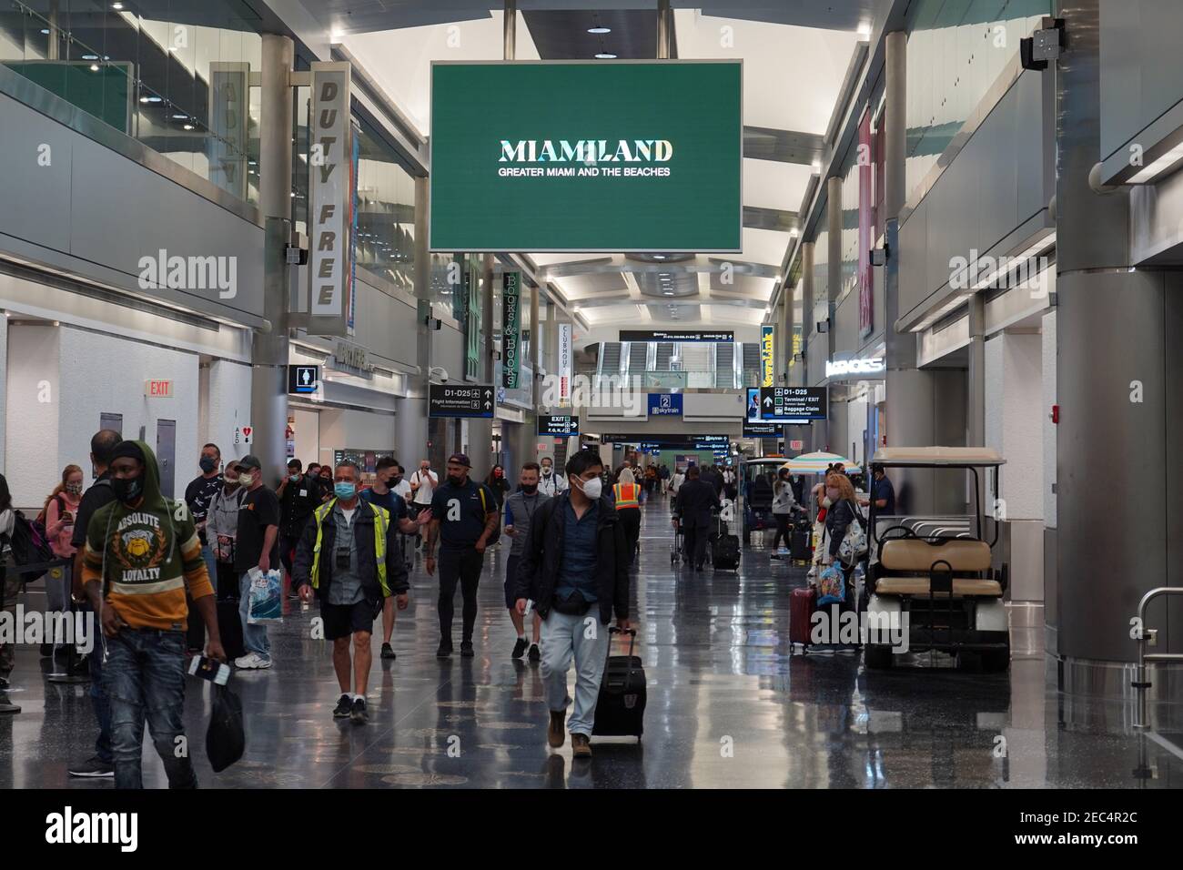 People walk through Terminal D of the Miami International Airport, Saturday, Feb. 13, 2021, in Miami. Stock Photo