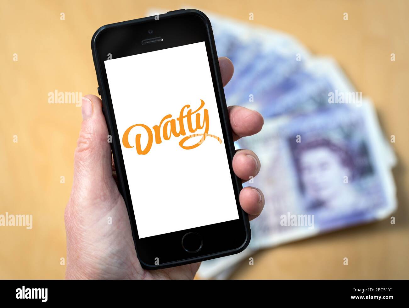 A woman looking at the Drafty App logo on her mobile phone. (editorial use only) Stock Photo