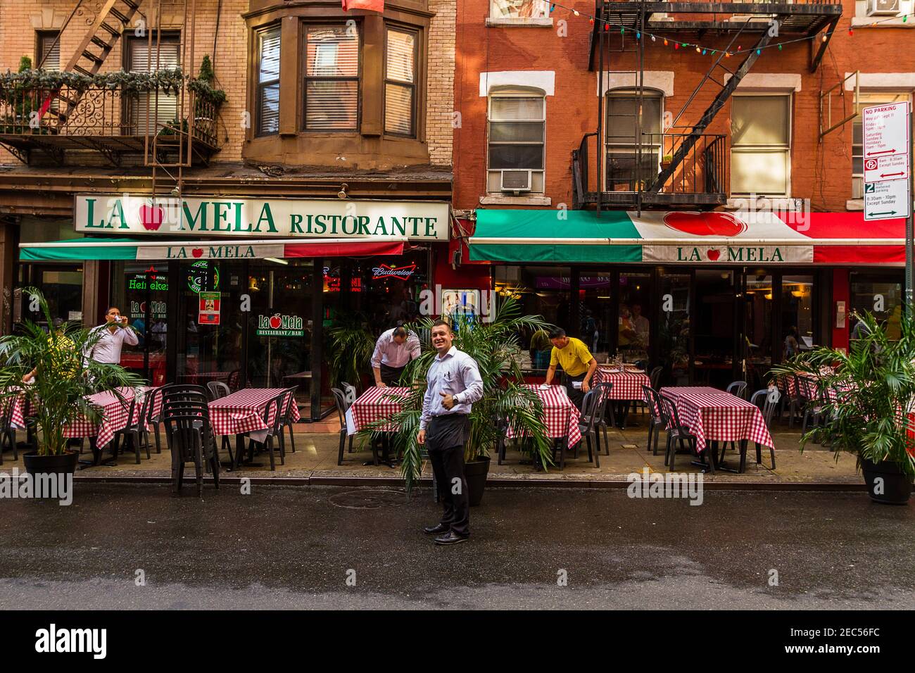 Waiters cleaning tables at the Italian Restaurant 'La Mela' in Little Italy and another waiter smiling and posing for the camera with his thumb up Stock Photo