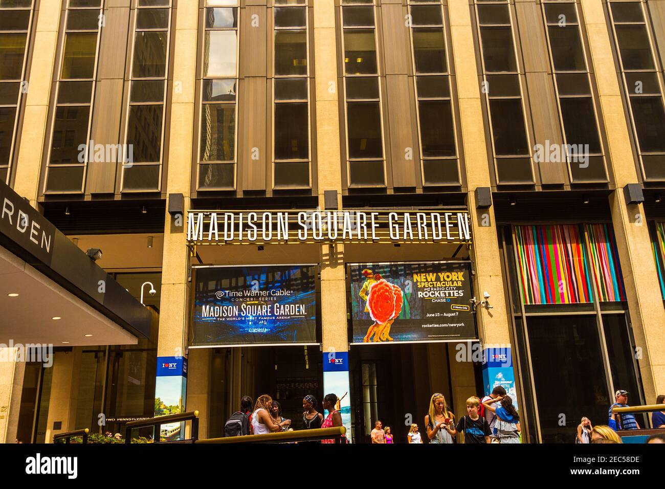 The Madison Square Garden signboard above the entrance of the arena with people talking and playing with their phones and texting at the entrance Stock Photo