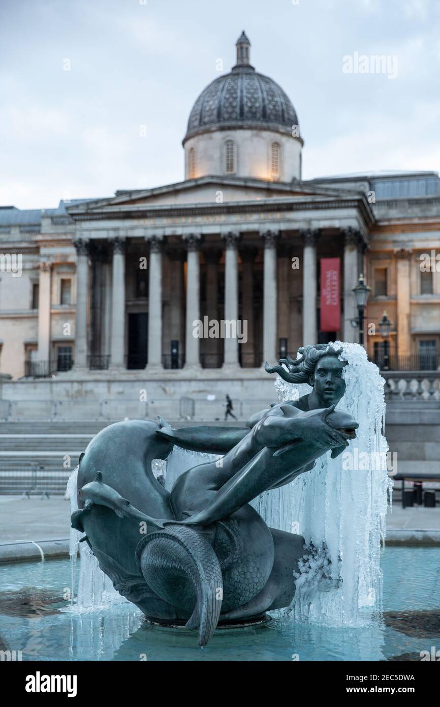Frozen statue in Trafalgar Square in the foreground of National Gallery after temperatures hit sub-zero temperatures in London during February 2021. Stock Photo