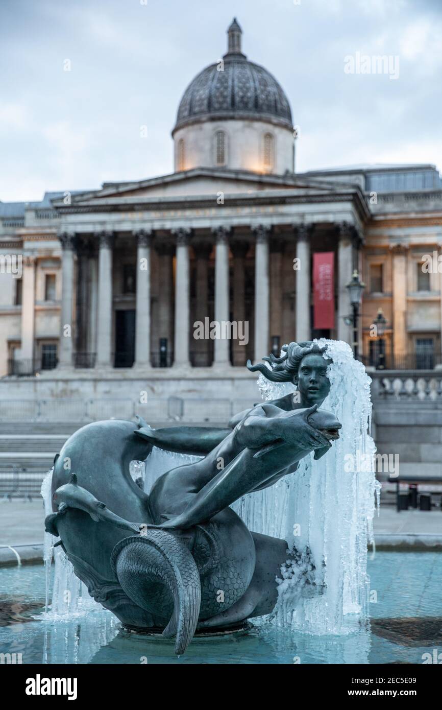 Frozen statue in Trafalgar Square in the foreground of National Gallery after temperatures hit sub-zero temperatures in London during February 2021. Stock Photo