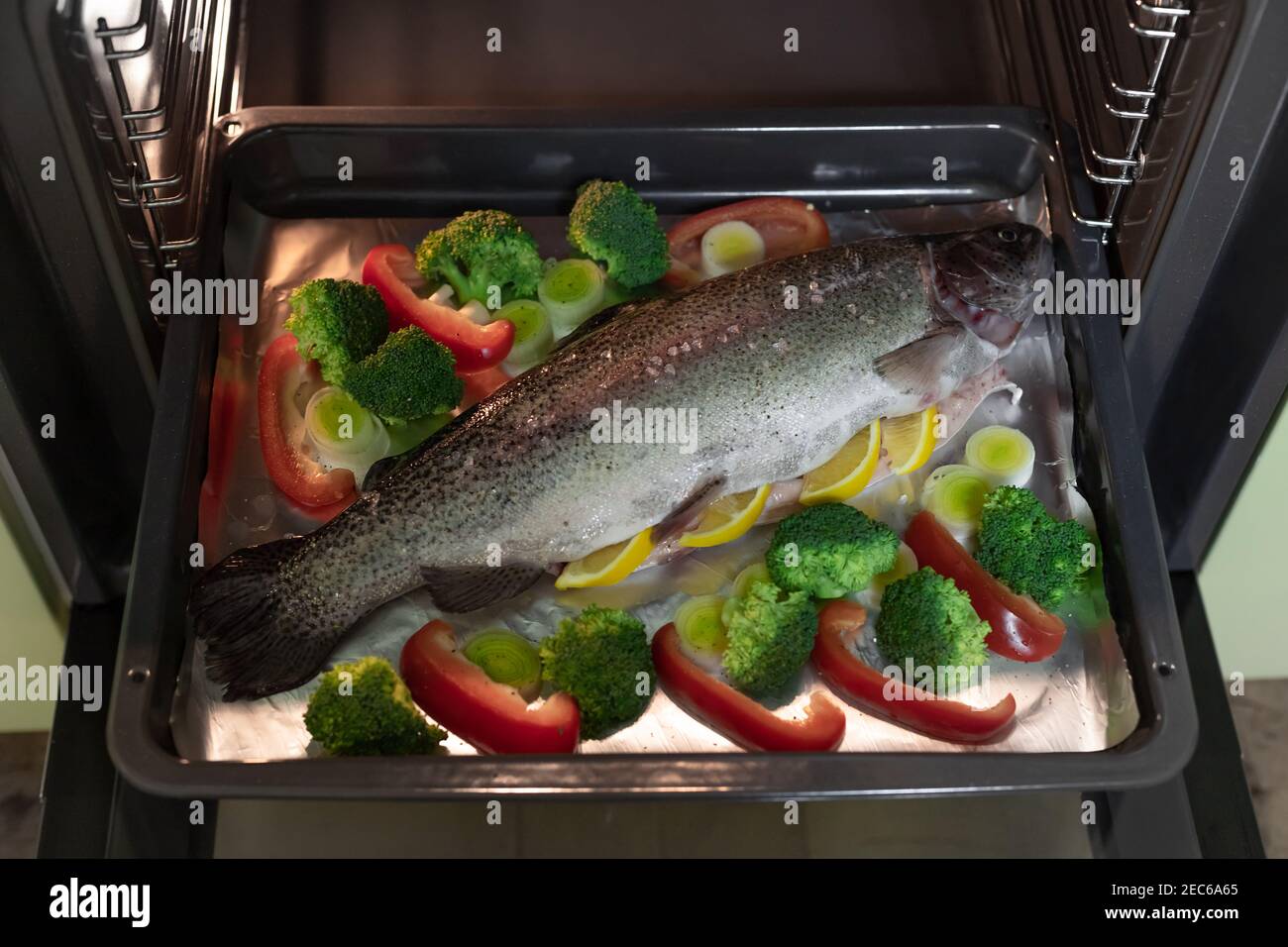 whole uncooked rainbow trout on baking tray in oven Stock Photo Alamy