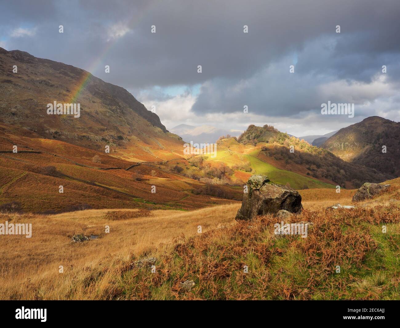 Rainbow arcing over Castle Crag and autumn colour near High Doat, Lake District Stock Photo