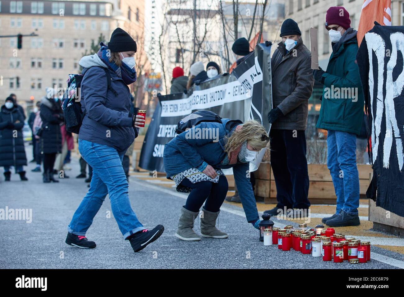 Hamburg, Germany. 13th Feb, 2021. Two women place devotional candles during a demonstration on the Jungfernstieg. More than 200 people demonstrated for accommodation of homeless people in hotels. Credit: Georg Wendt/dpa/Alamy Live News Stock Photo