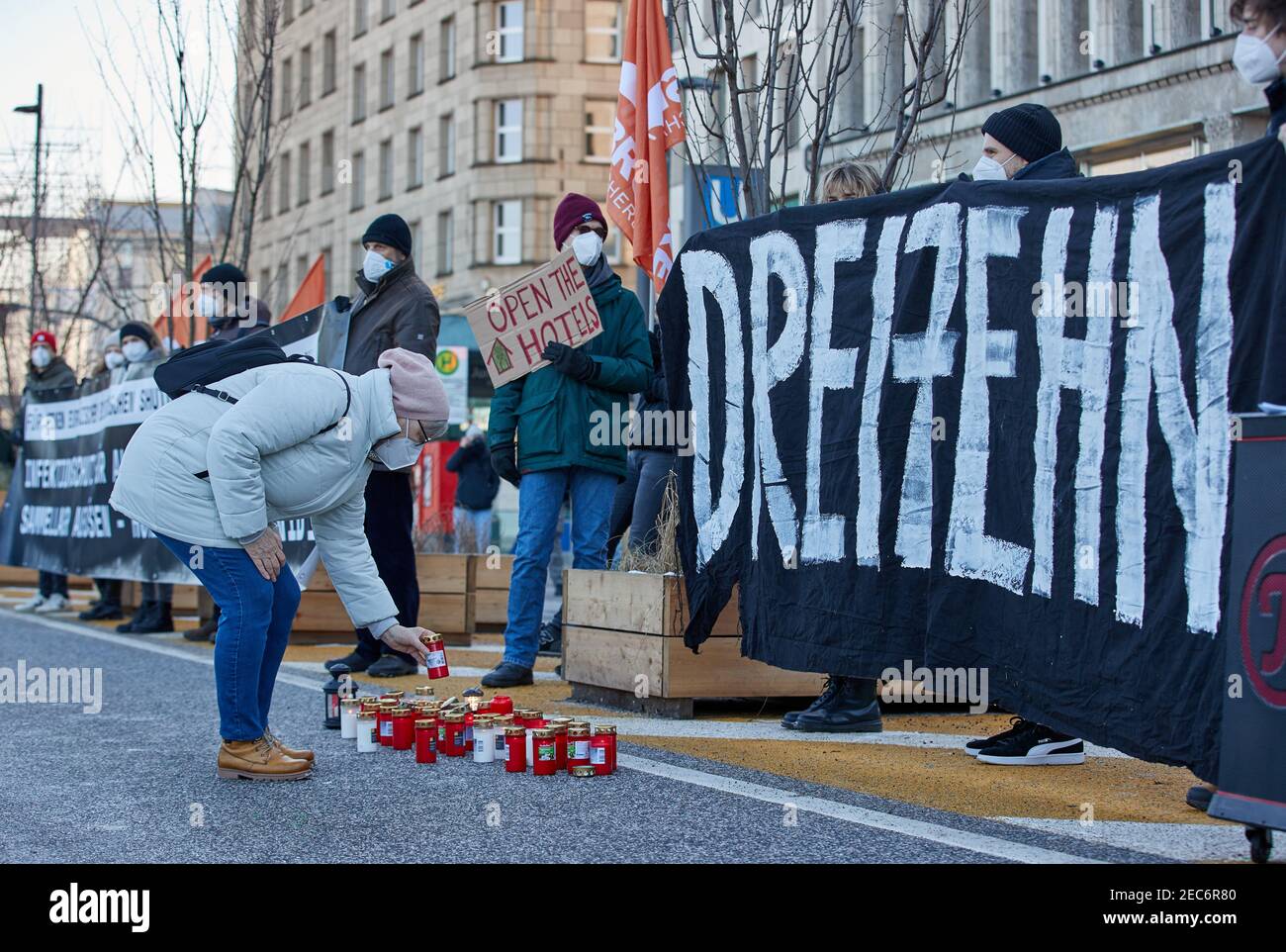 Hamburg, Germany. 13th Feb, 2021. A woman places a devotional candle during a demonstration on Jungfernstieg. Over 200 people demonstrated in favour of housing the homeless in hotels. Credit: Georg Wendt/dpa/Alamy Live News Stock Photo