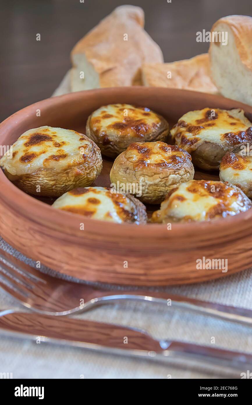 Mushrooms, Sulguni Cheese in Clay Pots, pita and cutlery close up on the table. Georgian traditional food Stock Photo