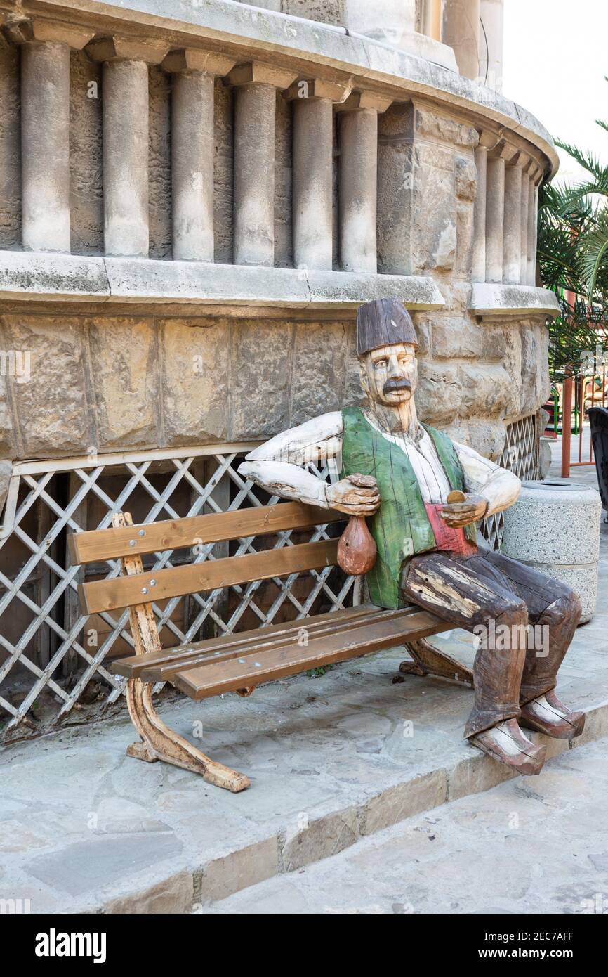 Carved statue of a man sitting on a bench in Veliko Tarnovo Stock Photo