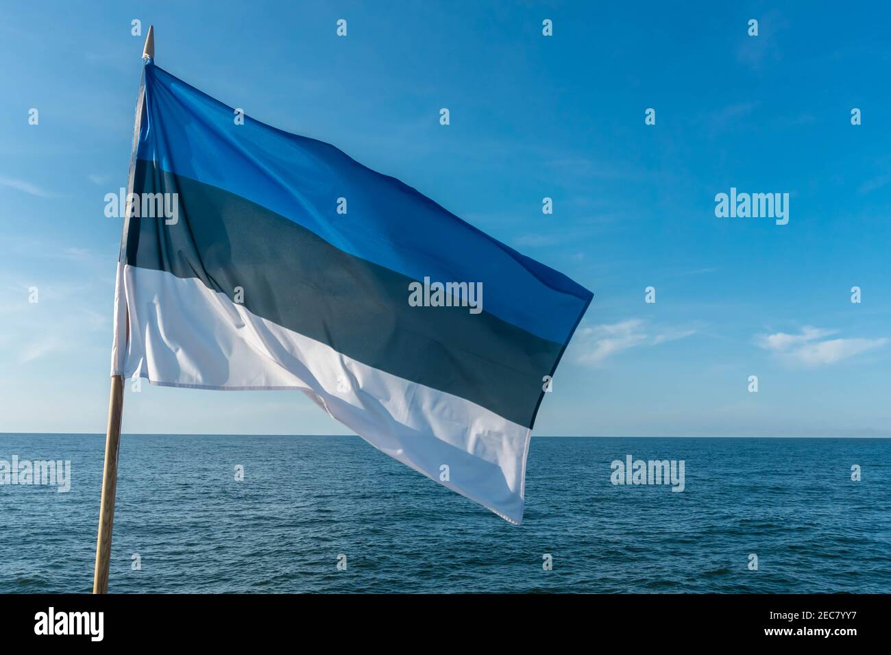 Flag of Estonia on blue sky background flying in strong breeze over the ...