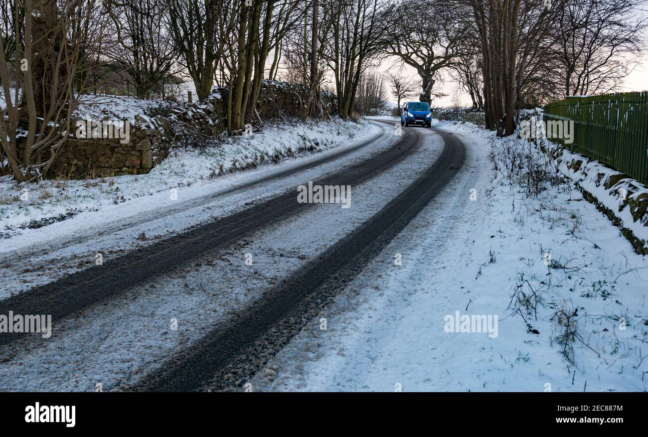 Van driving round bend on snow covered country road in Winter, East Lothian, Scotland, UK Stock Photo