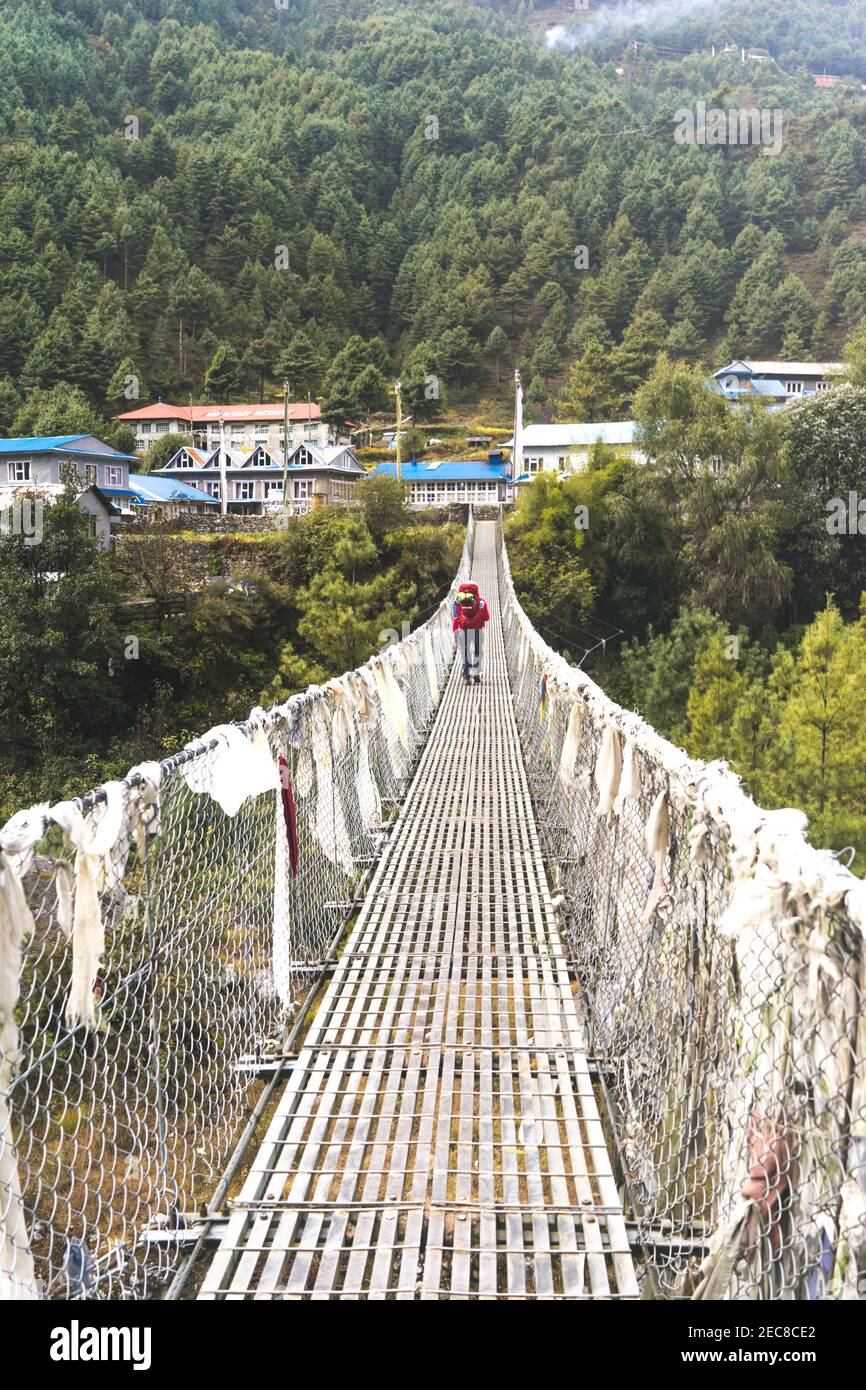 bridge over the river, solo trekker on the suspension bridge in Nepal, trekking in the Himalayas, Everest Base Camp, Annapurna Circle Stock Photo