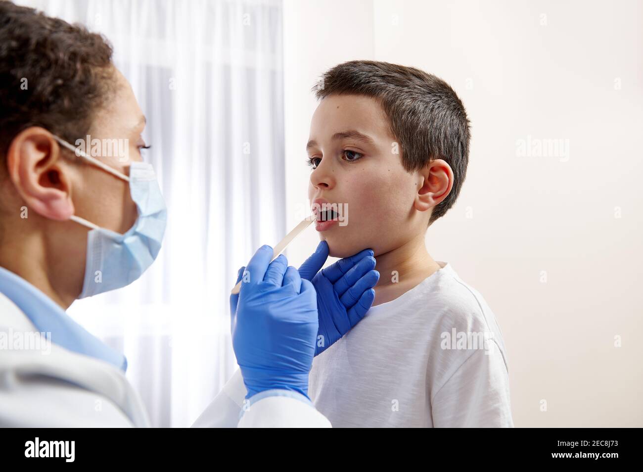 Pediatrician examining little boys throat to diagnose his illness. Stock Photo