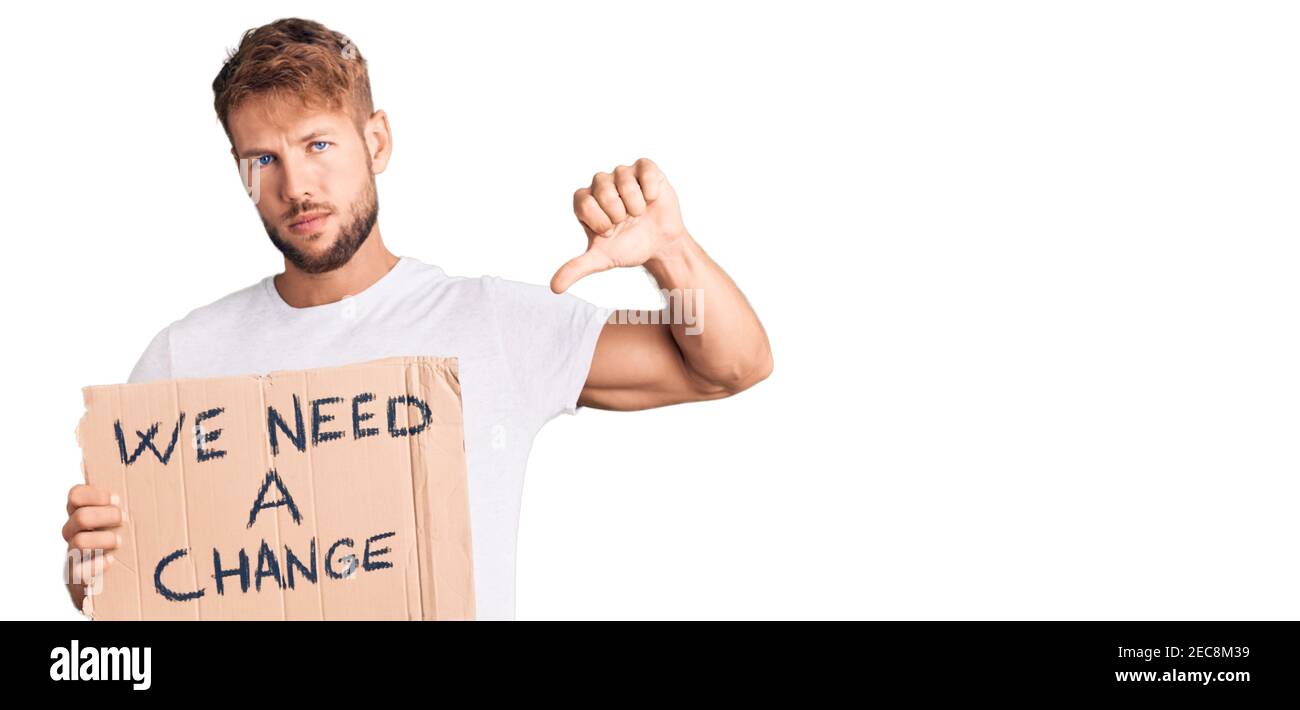 Young caucasian man holding we need a change banner with angry face ...