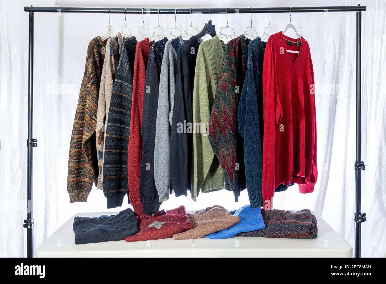 Horizontal shot of a group of men’s sweaters displayed at an estate sale or garage sale. Stock Photo