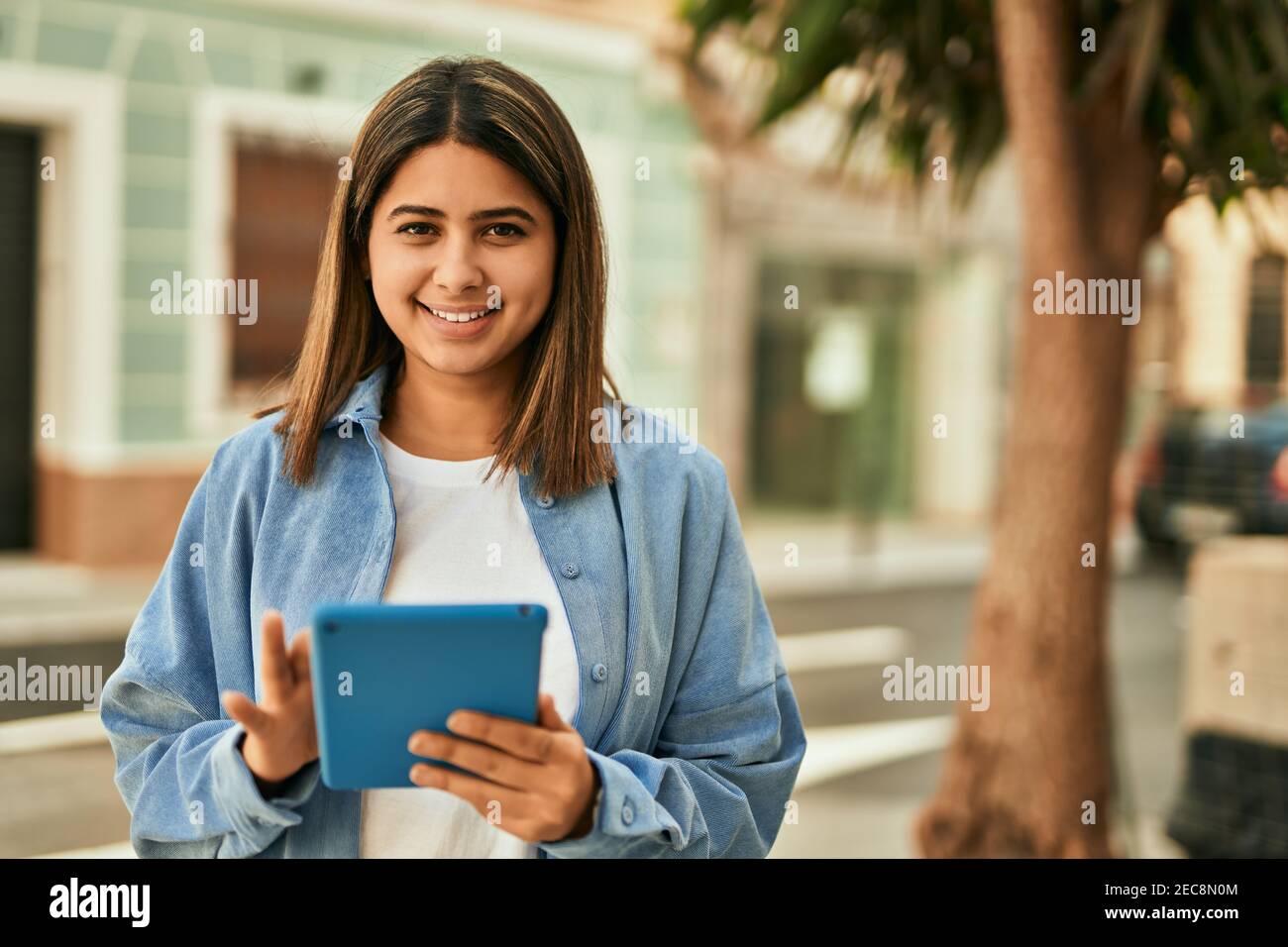 Young latin girl smiling happy using touchpad at the city Stock Photo ...