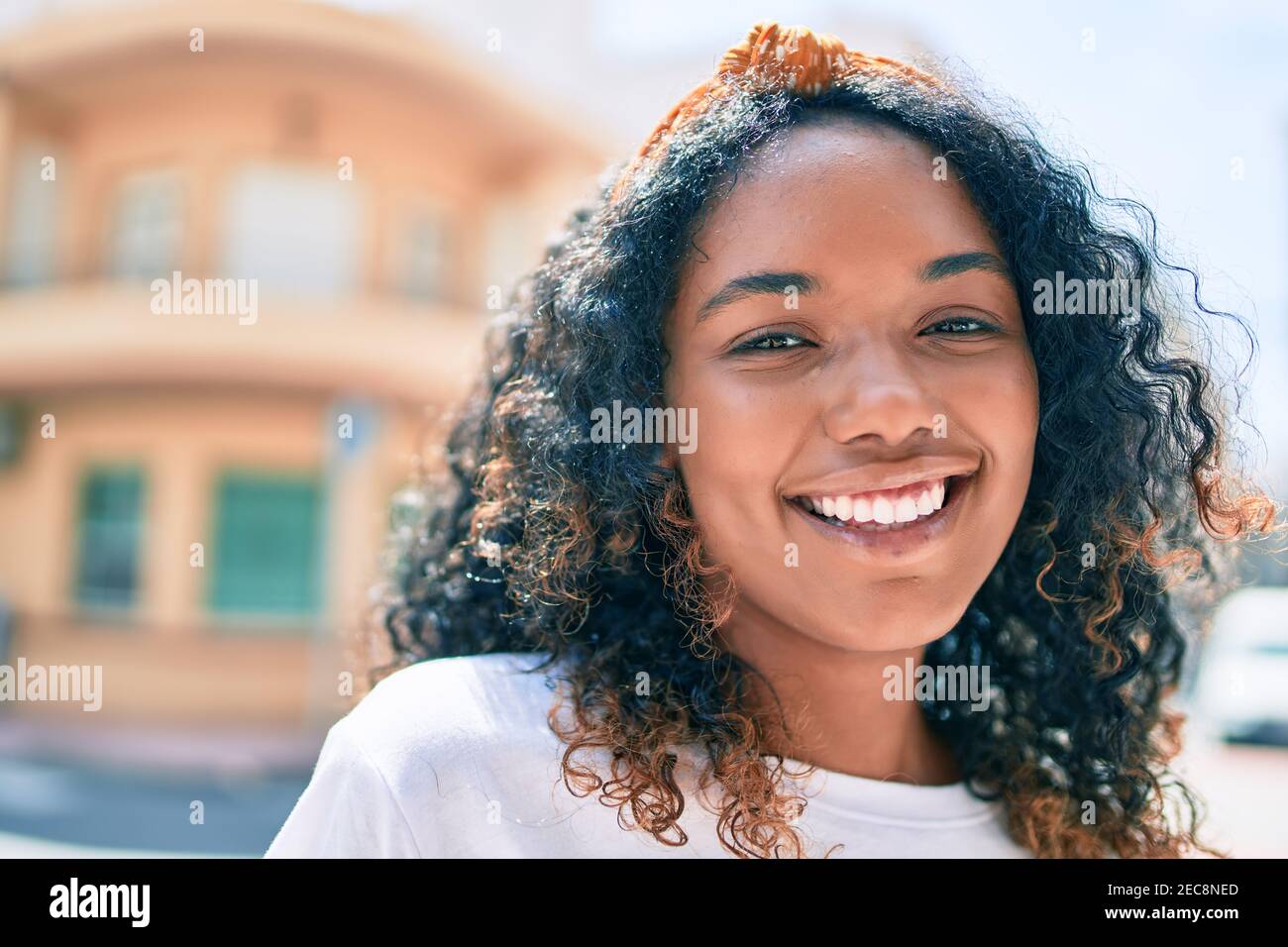 Young african american woman with curly hair smiling happy outdoors ...
