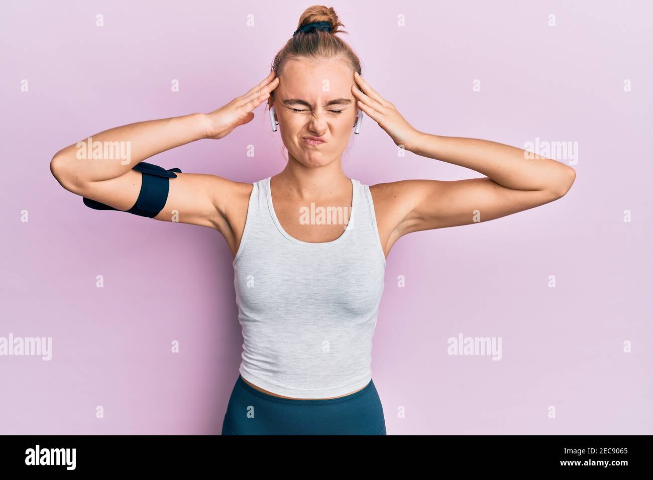 Beautiful blonde sport woman wearing arm band and earphones with hand