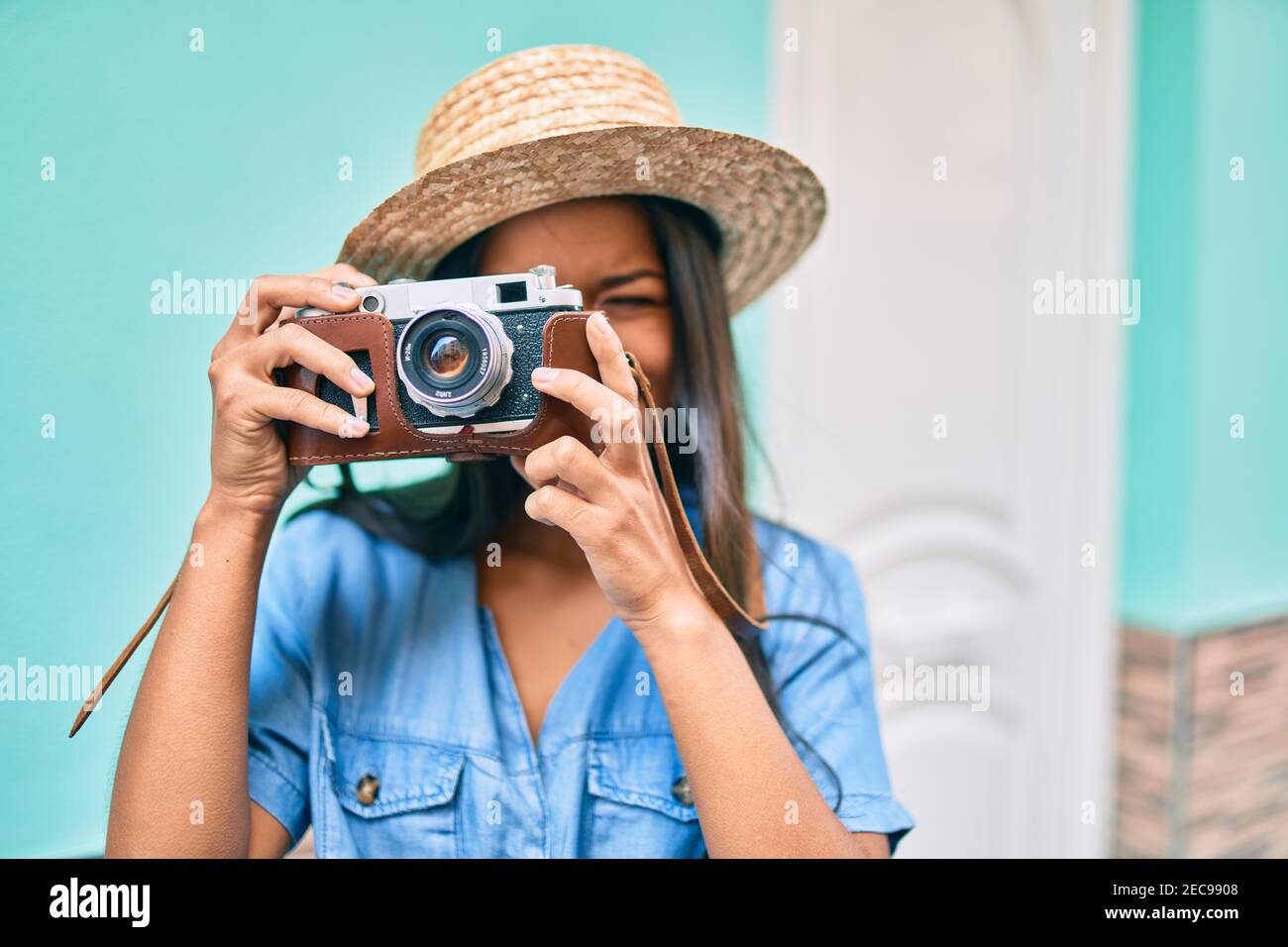 Young latin tourist girl on vacation smiling happy using vintage camera ...