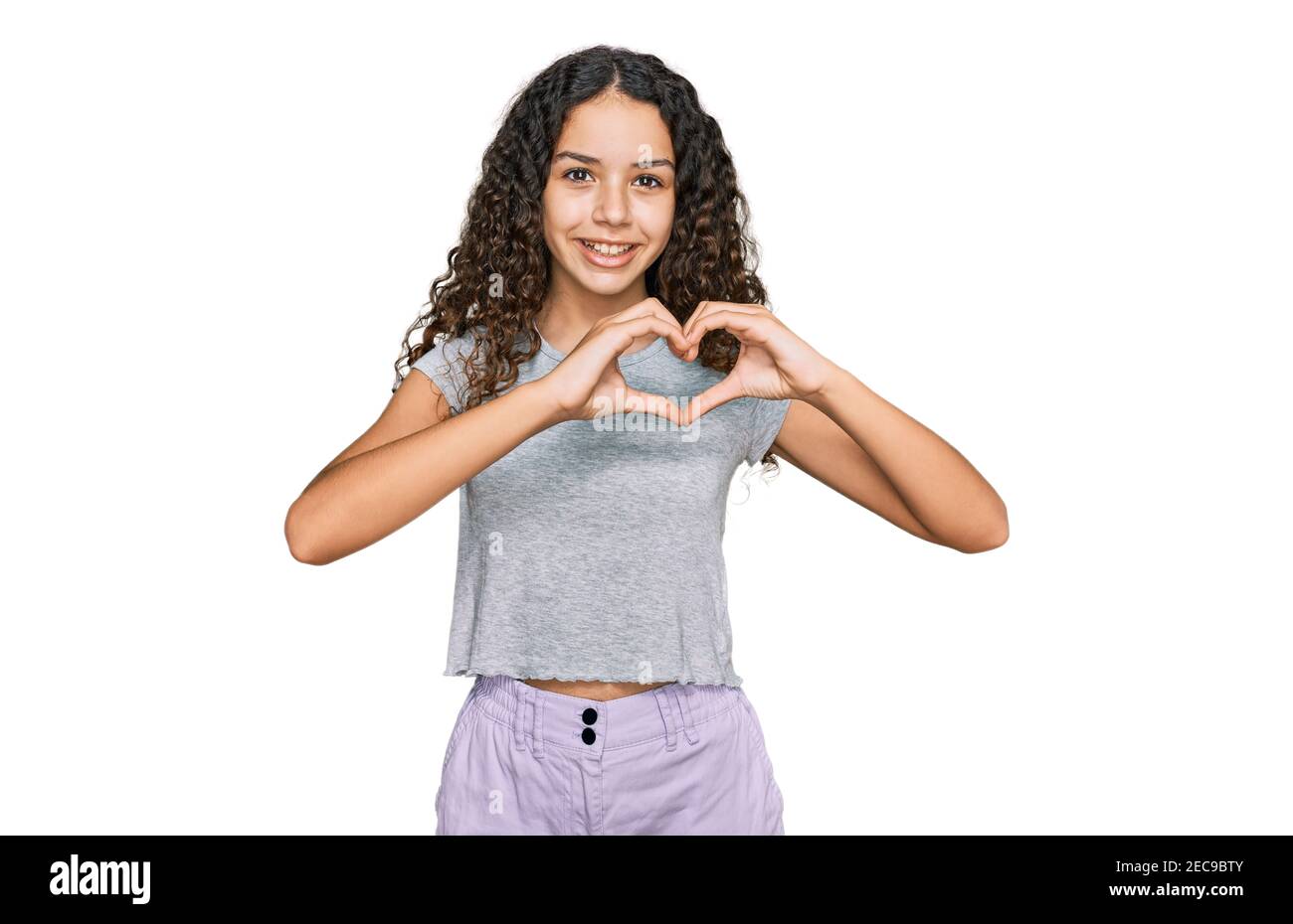 Teenager hispanic girl wearing casual clothes smiling in love showing heart symbol and shape with hands. romantic concept. Stock Photo