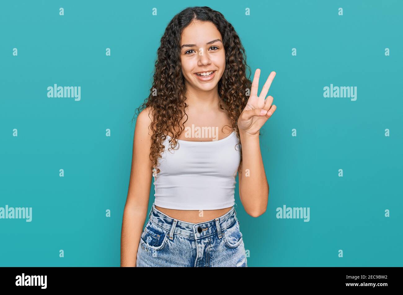 Teenager hispanic girl wearing casual clothes showing and pointing up with fingers number two while smiling confident and happy. Stock Photo