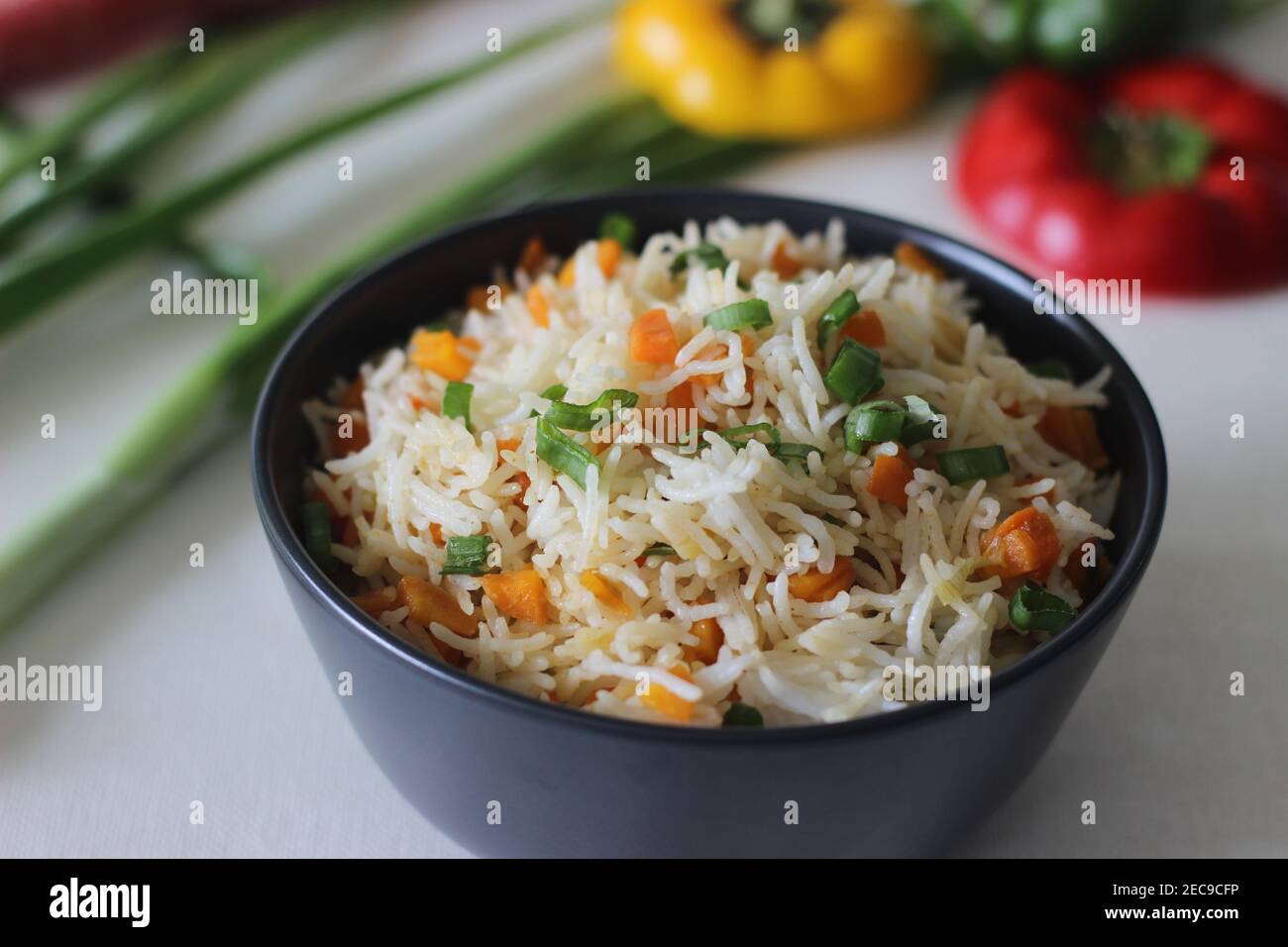 Vegetable Carrot Fried Rice with Indian spices. Shot on white back ground along with carrots and spring onions Stock Photo