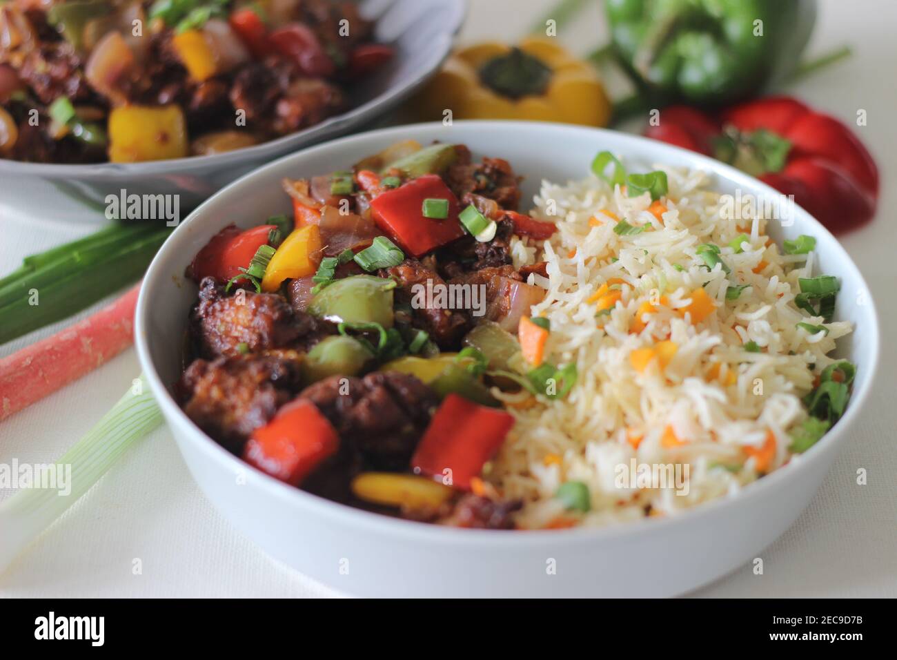 Vegetable Carrot Fried Rice with Indian spices served along with chilly chicken. Homemade food shot on white background Stock Photo