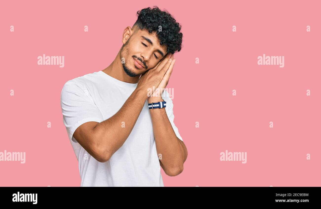Young arab man wearing casual white t shirt sleeping tired dreaming and ...