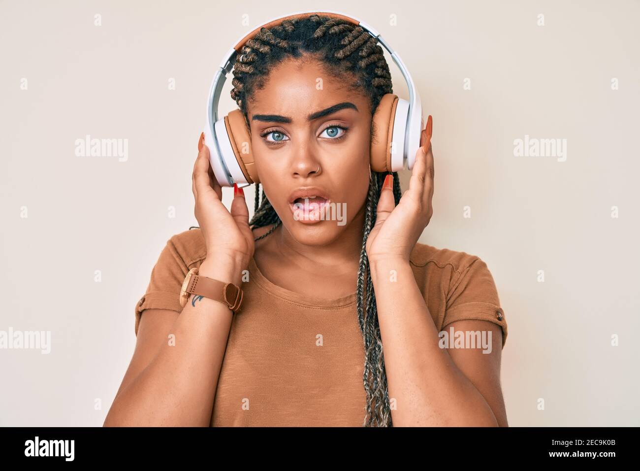 Young african american woman with braids listening to music using ...