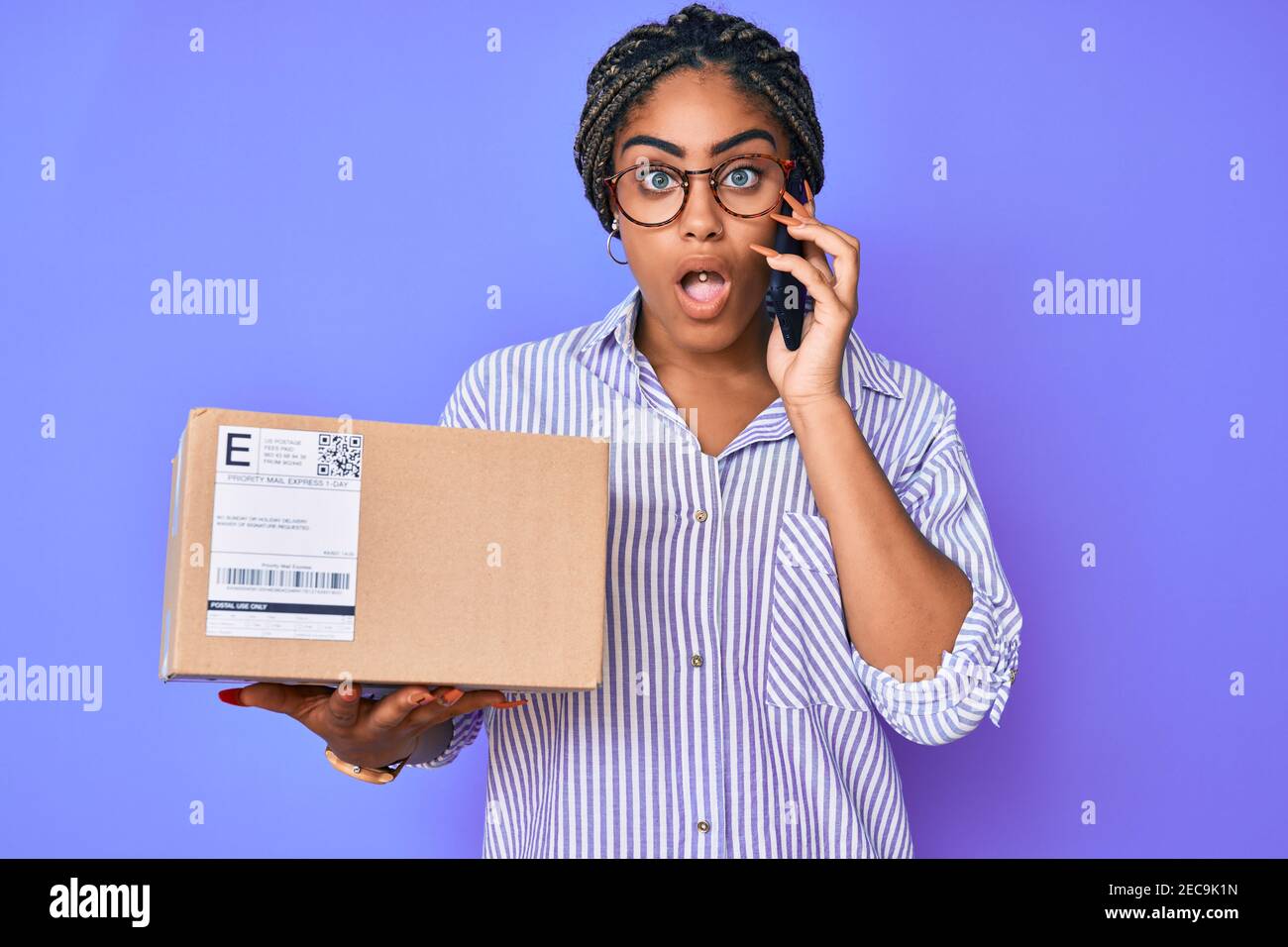 Young african american woman with braids holding delivery box calling
