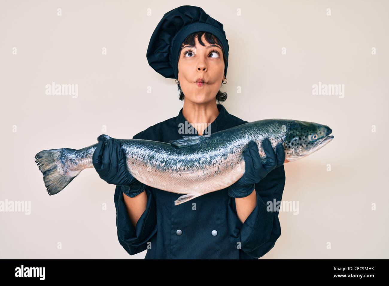 Beautiful brunettte woman professional chef holding fresh salmon