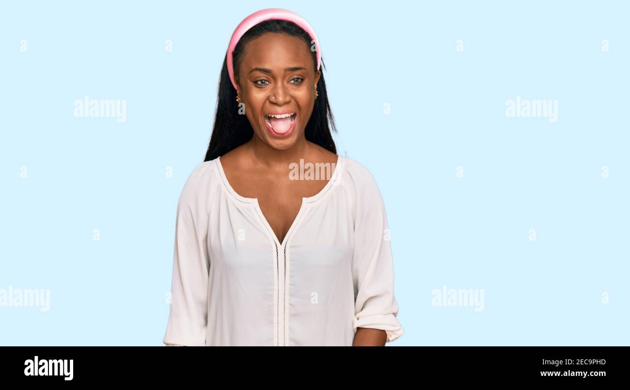 Young black woman wearing casual clothes sticking tongue out happy with ...