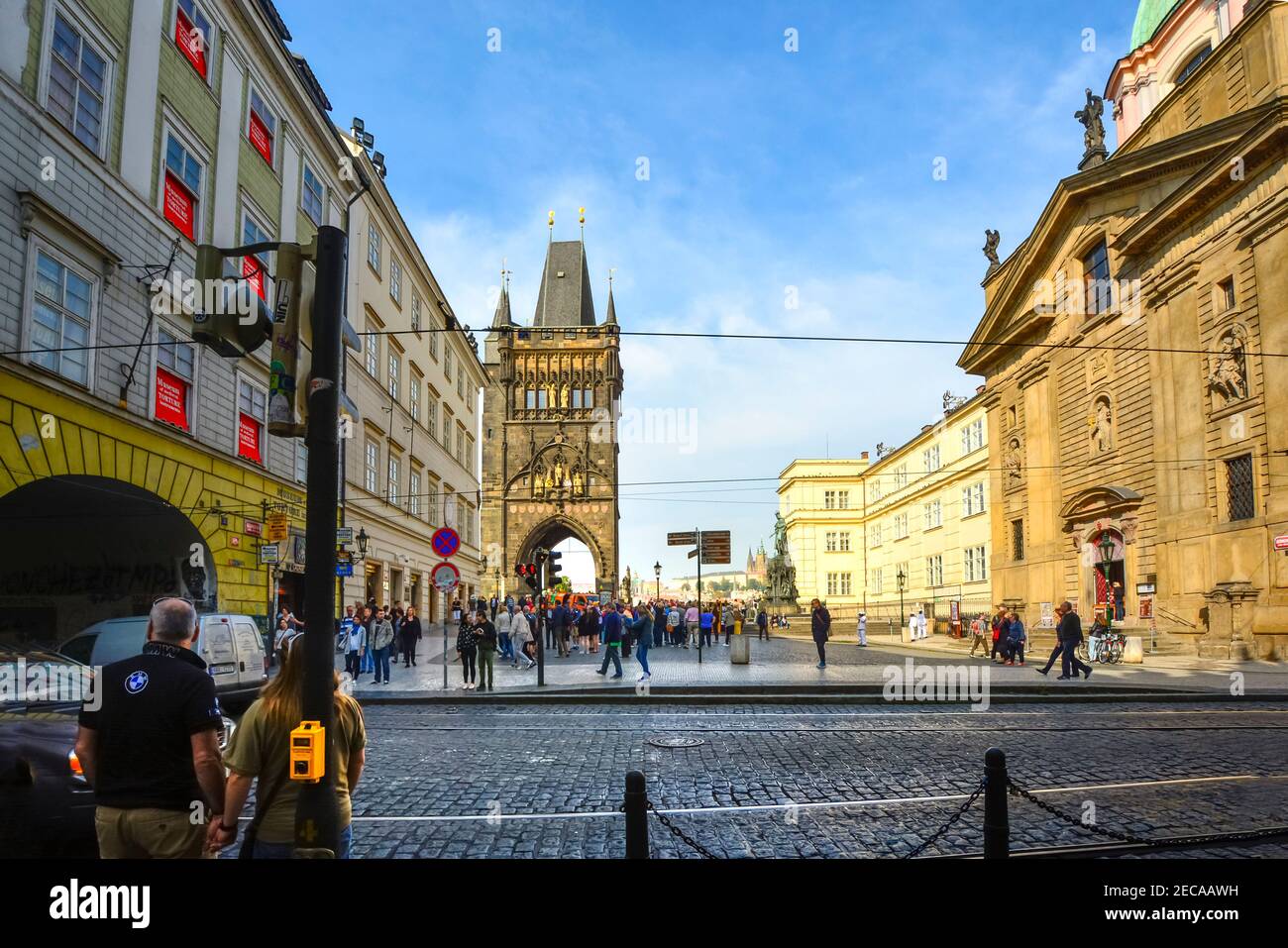 Pedestrians prepare to cross the street towards Knights of the Cross Square with the Old Town Tower and St Vitus Cathedral in view in Prague Czechia. Stock Photo