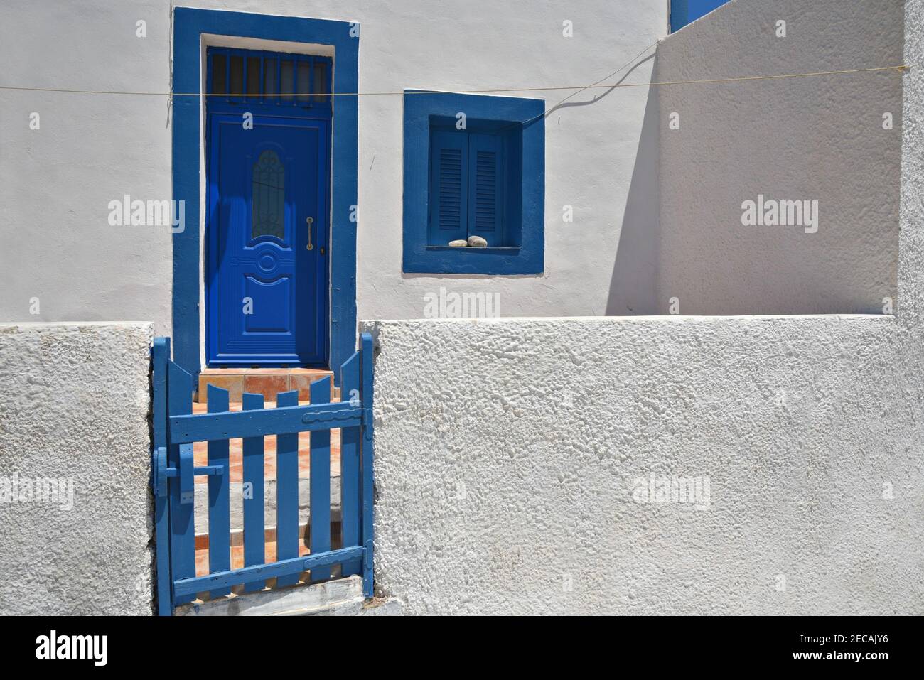 Traditional rural house facade with whitewashed walls, blue wooden door ...