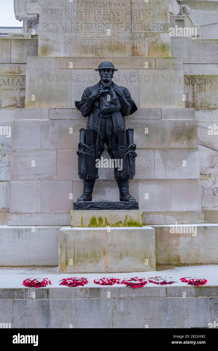 Bronze figure of a standing soldier on the Royal Artillery Memorial with poppy wreaths and snow, Hyde Park Corner, London, UK Stock Photo