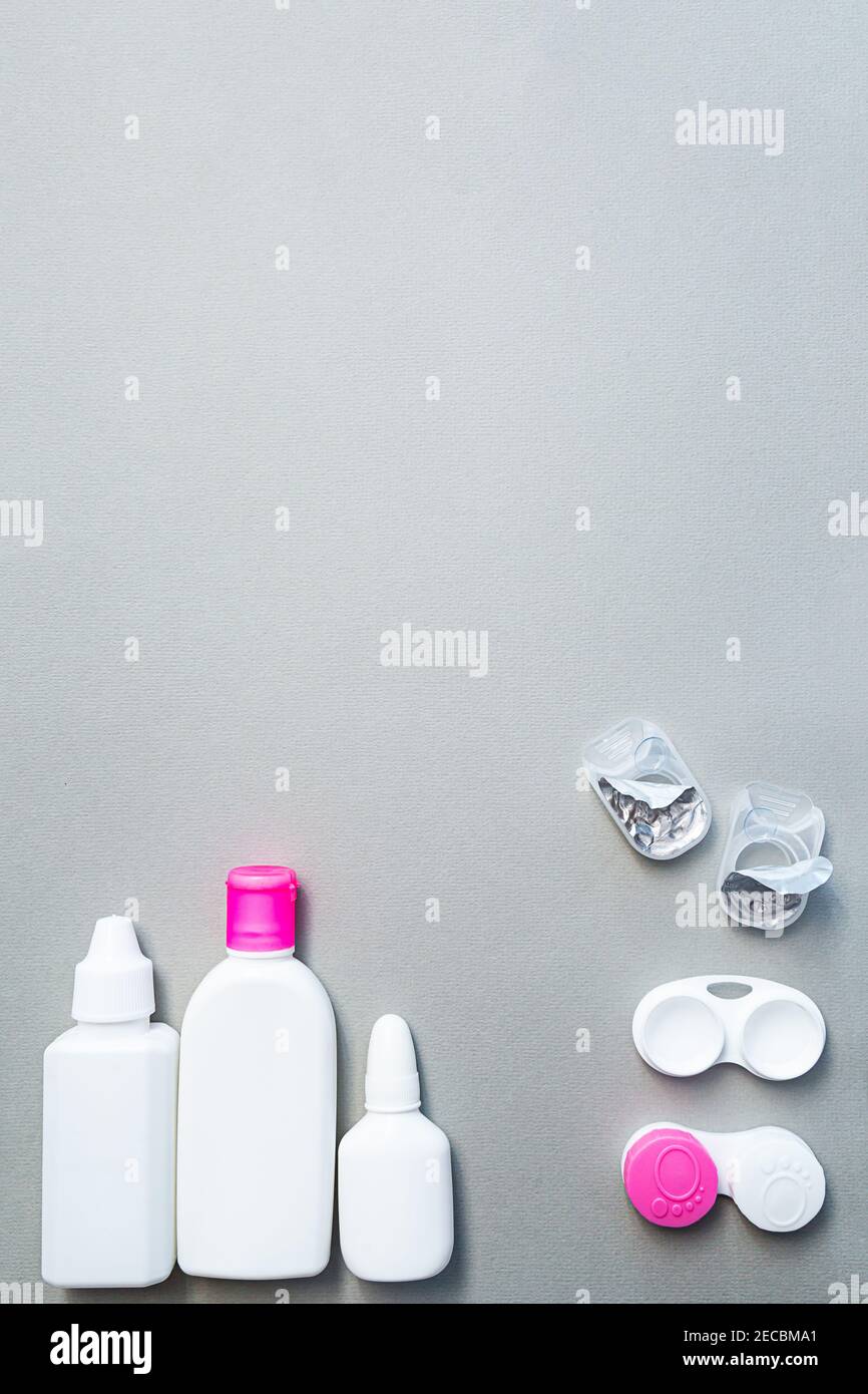 Contact lenses and accessories flat lay on a gray background. Composition with solution bottles and lens containers with copy space Stock Photo