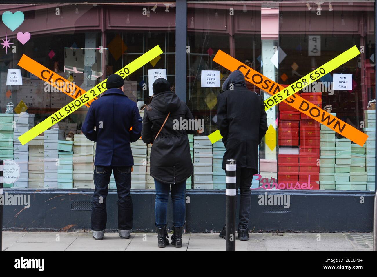 Dublin, Ireland. 12th Feb, 2021. People look through the window of a closed shoe  shop in Dublin city center, during the COVID-19 pandemic lockdown.Level 5  lockdown restrictions are set to be extended
