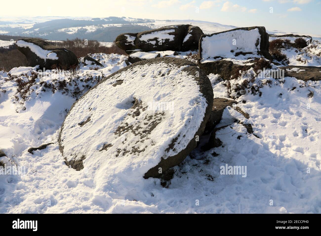 Snow covered Derbyshire mill stone cut from Millstone Grit in the Peak District National Park Stock Photo