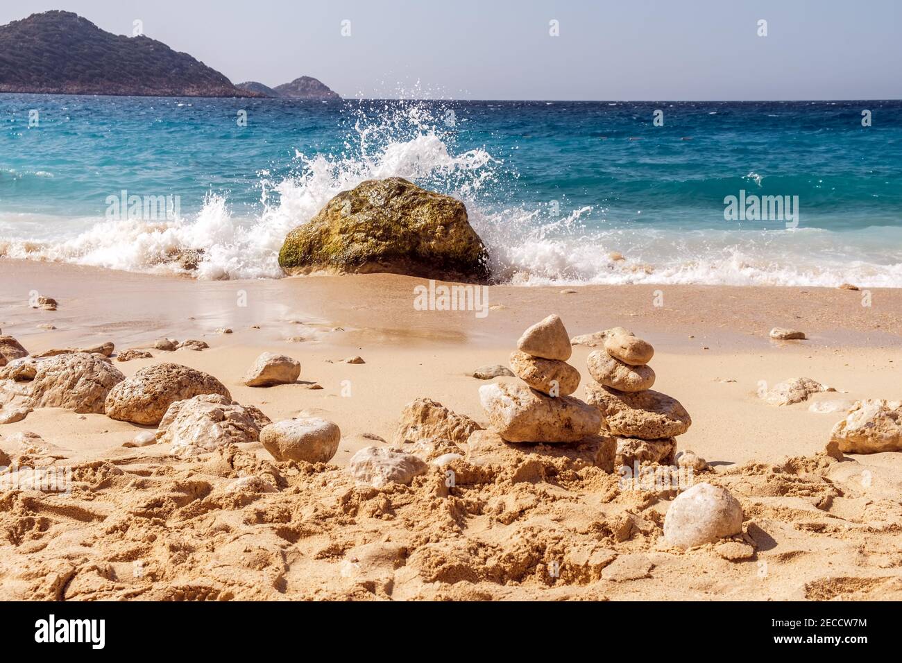 Summer landscape, waves with brakes break on a stone, a cairn of stones in the sand, Kaputas beach, Turkey. Stock Photo