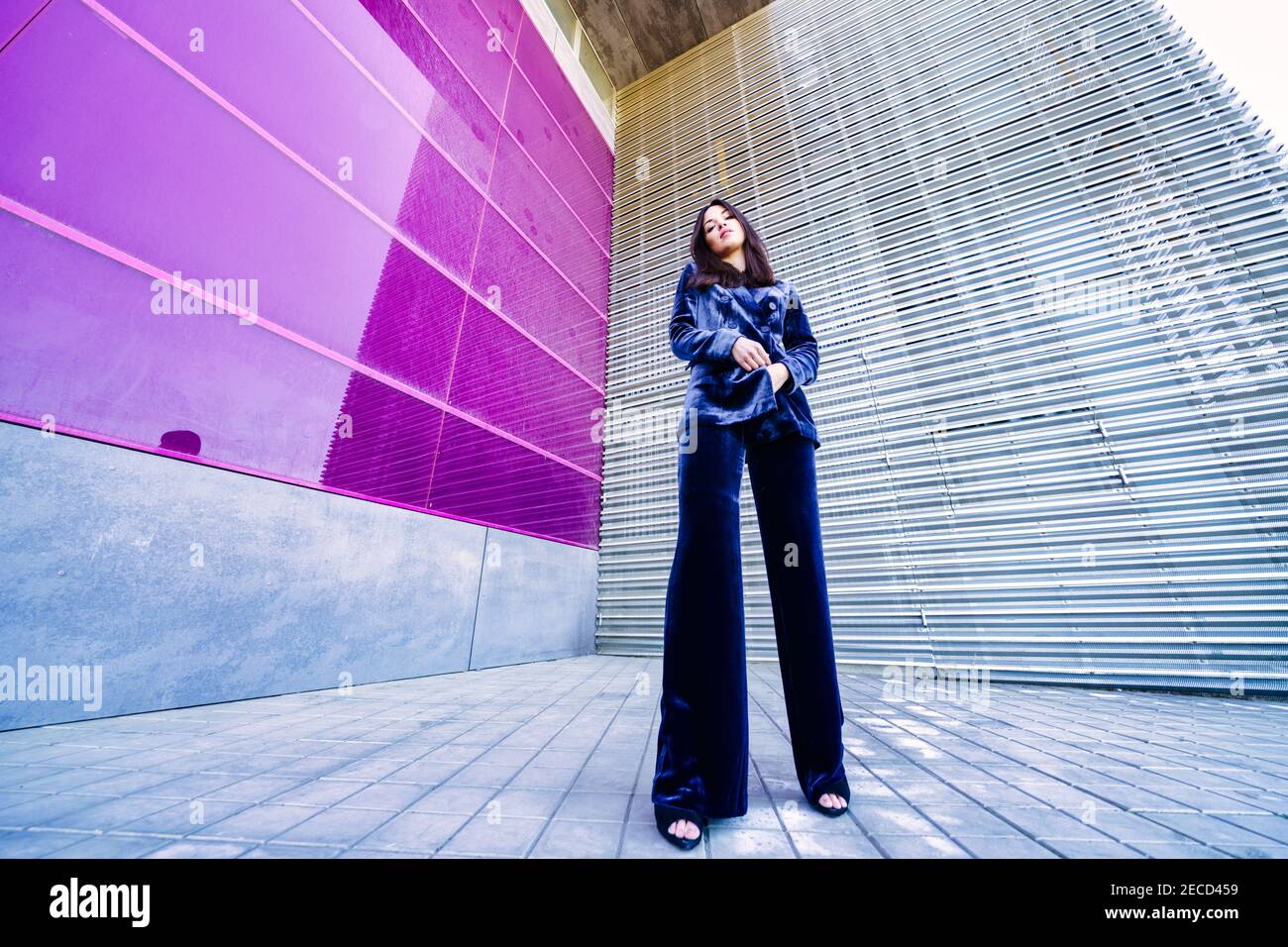 Wide-angle photo of a woman wearing blue suit posing near a modern building. Stock Photo