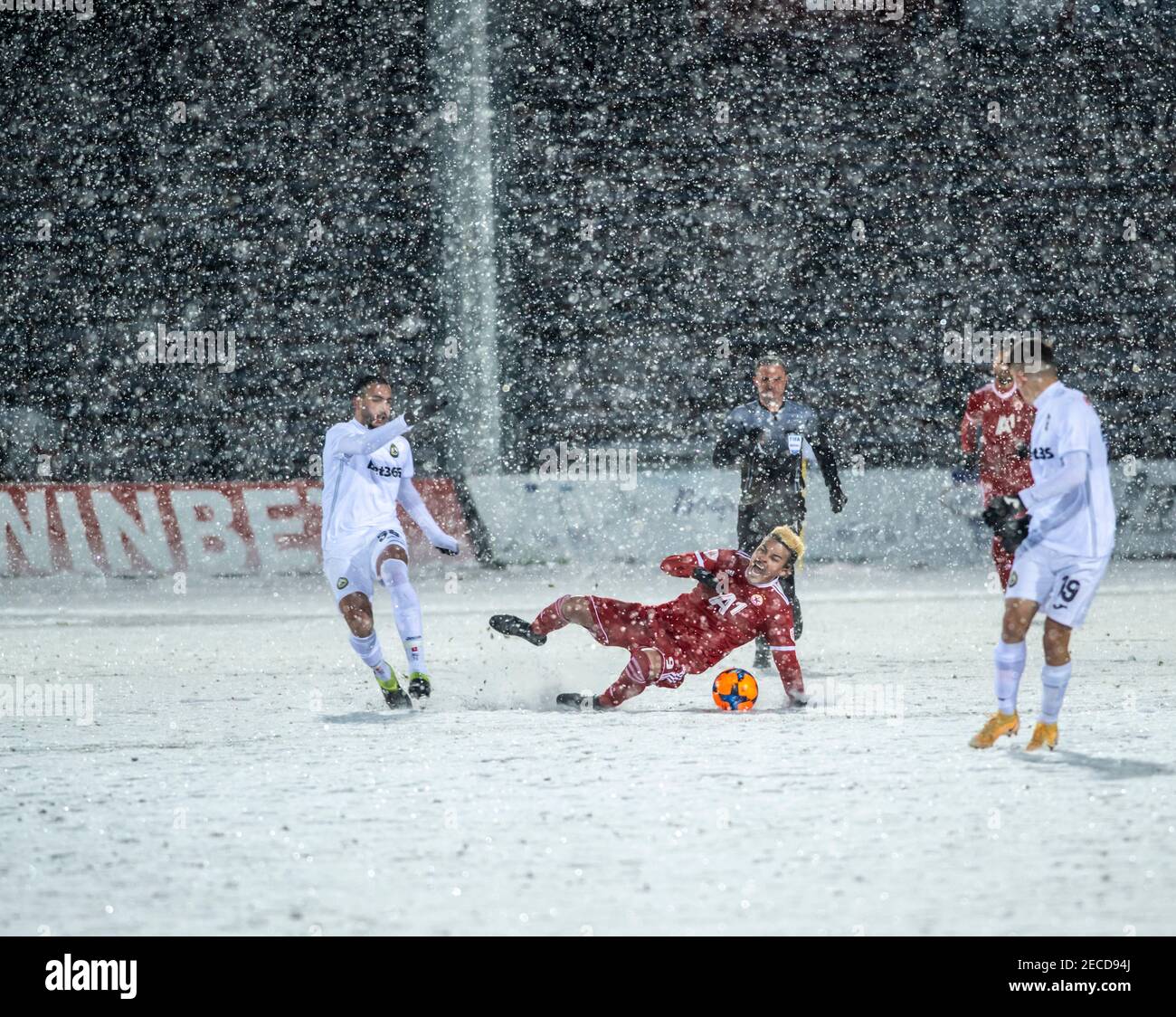 Sofia, Bulgaria - Feb 13 2021: Penaranda falling with the ball on the snowy ground during a snowy football match between CSKA Sofia and Slavia Stock Photo