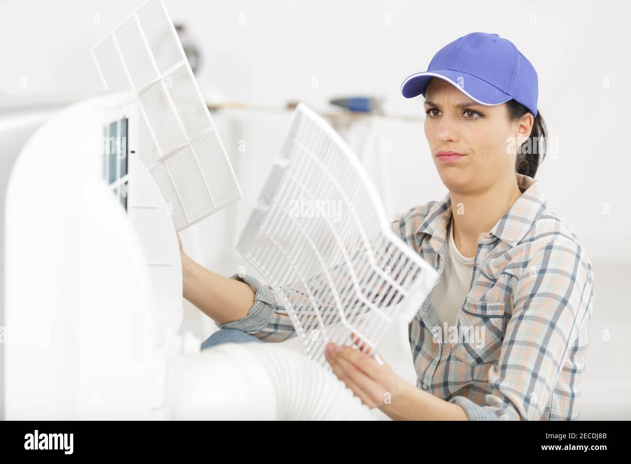 young woman checking and cleaning air conditioning system at home Stock Photo