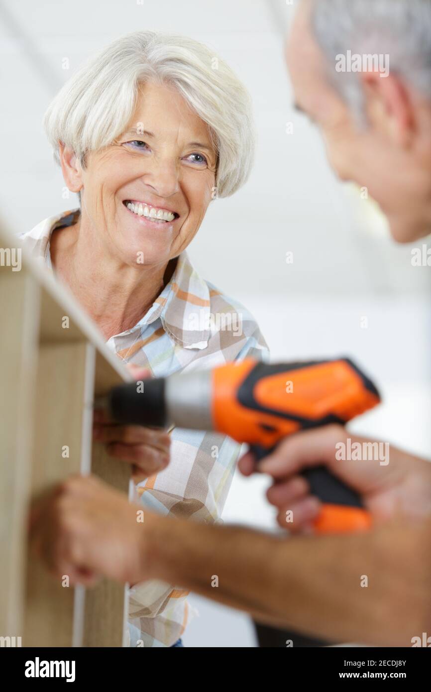 woman smiling at man using an electronic drill Stock Photo