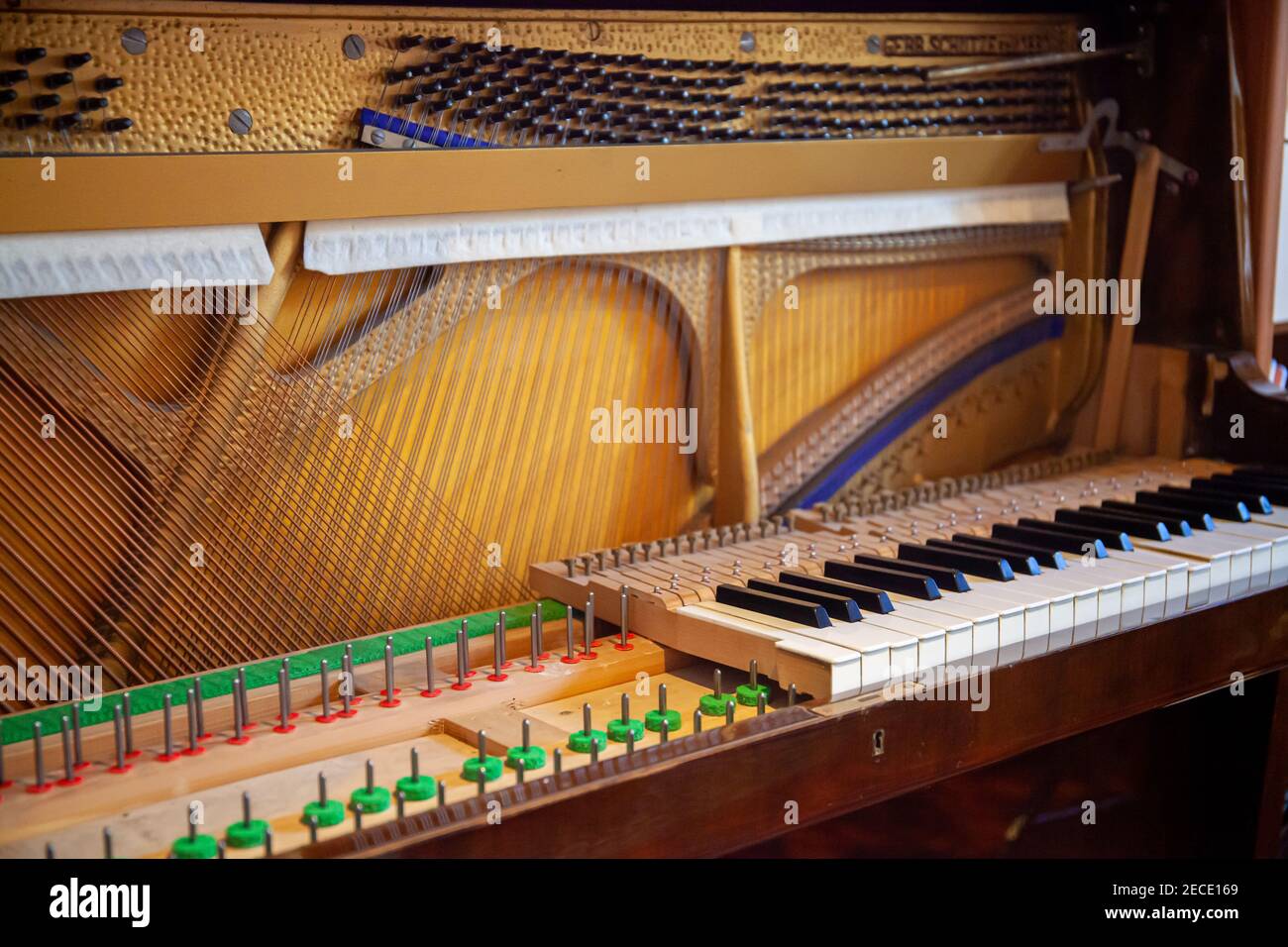 Disassembled upright piano for repair, service, tuning, cleaning. Open piano with sound board and string visible. Stock Photo