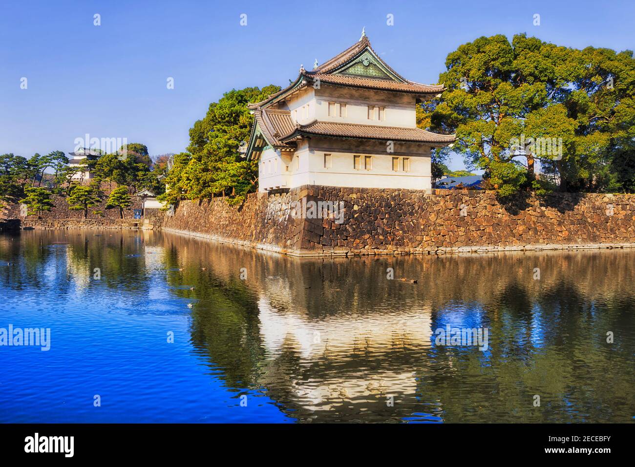 Historic corner stone towers on perimeter of green garden in Tokyo of Japan surrounded by water filled moat. Stock Photo