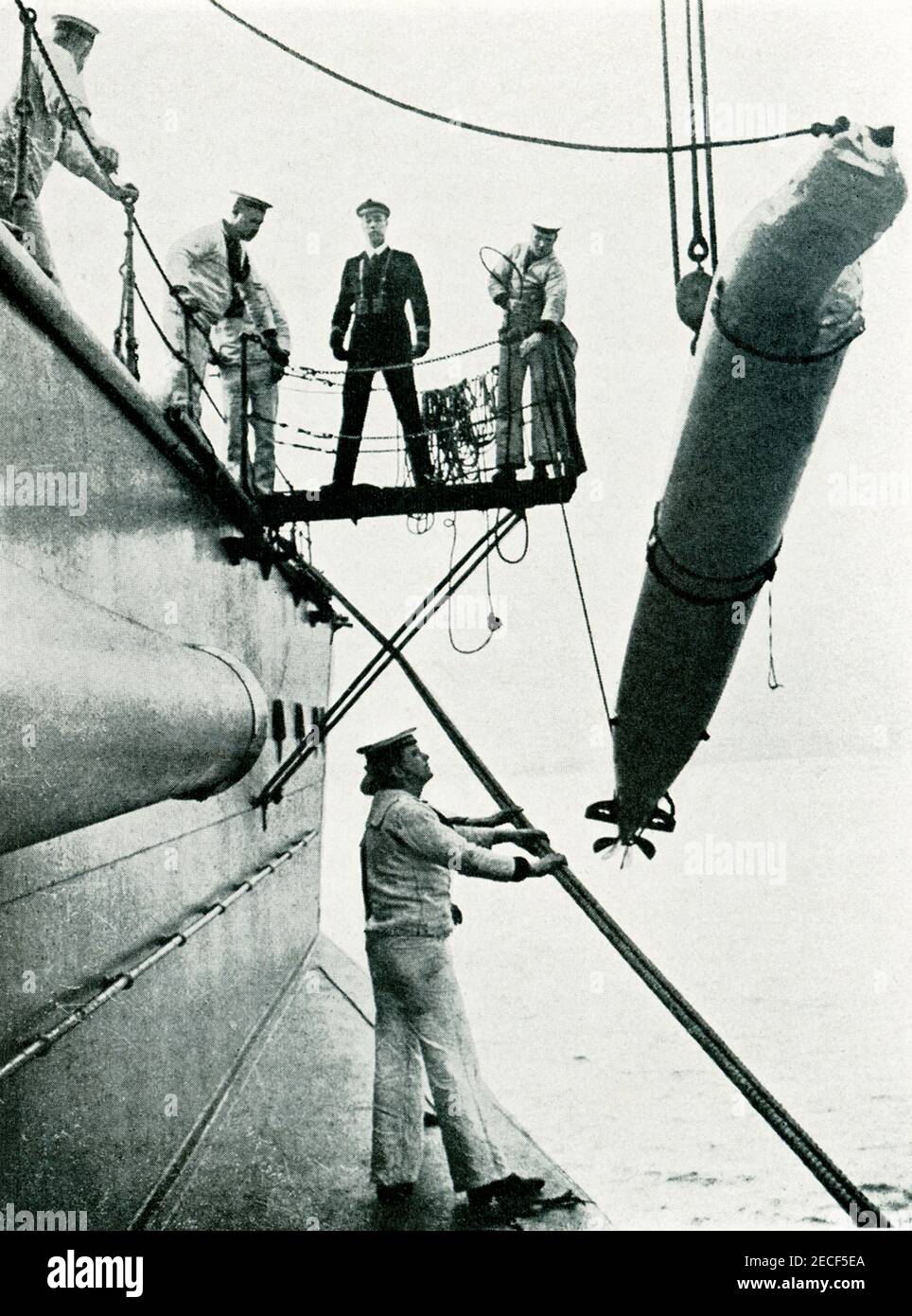 This photo from world war I shows a practice torpedo being hoisted over the side of a British ship. Stock Photo